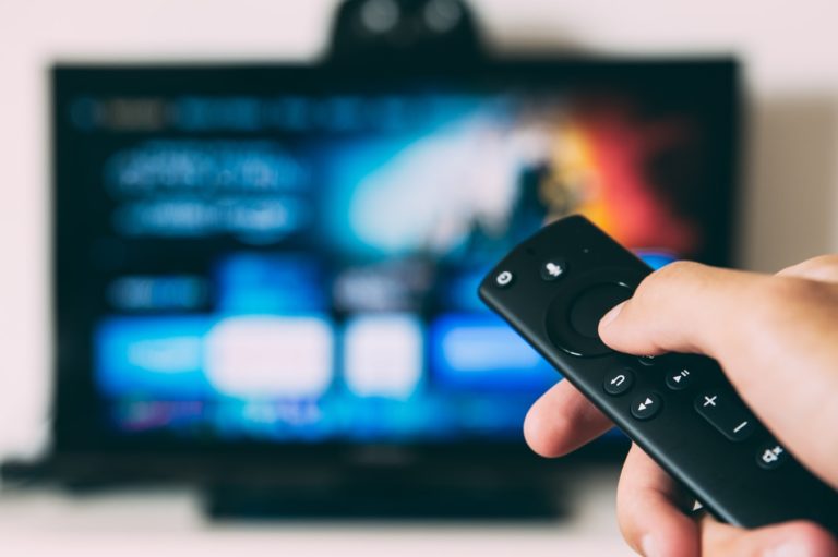 Un homme manipulant sa télécommande devant une télévision