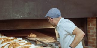 Un boulanger mettant du pain au four.