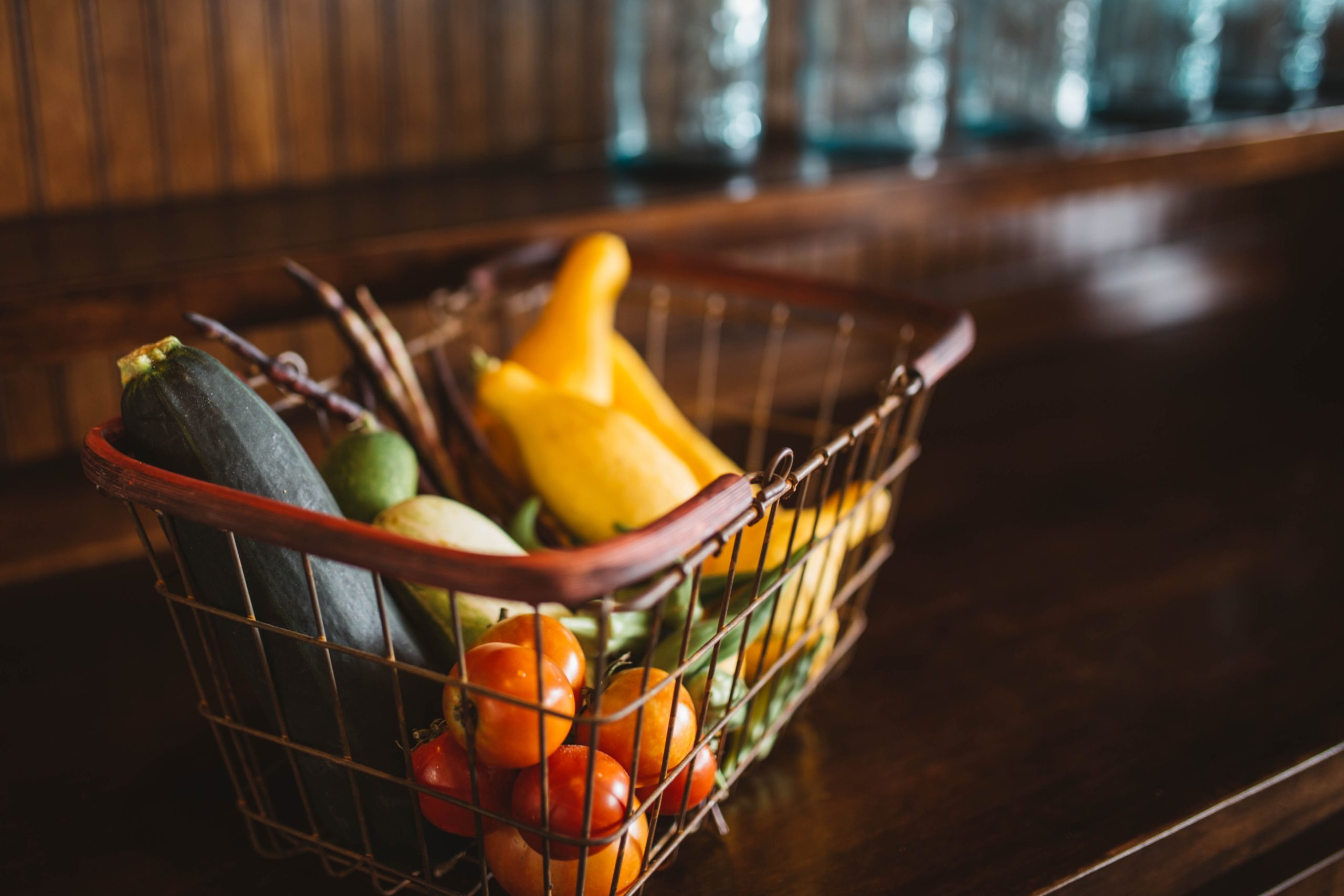 Des fruits et légumes dans un panier sur une table en cuisine.